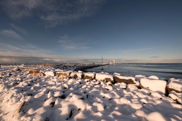 rocks covered by snow next to the sea