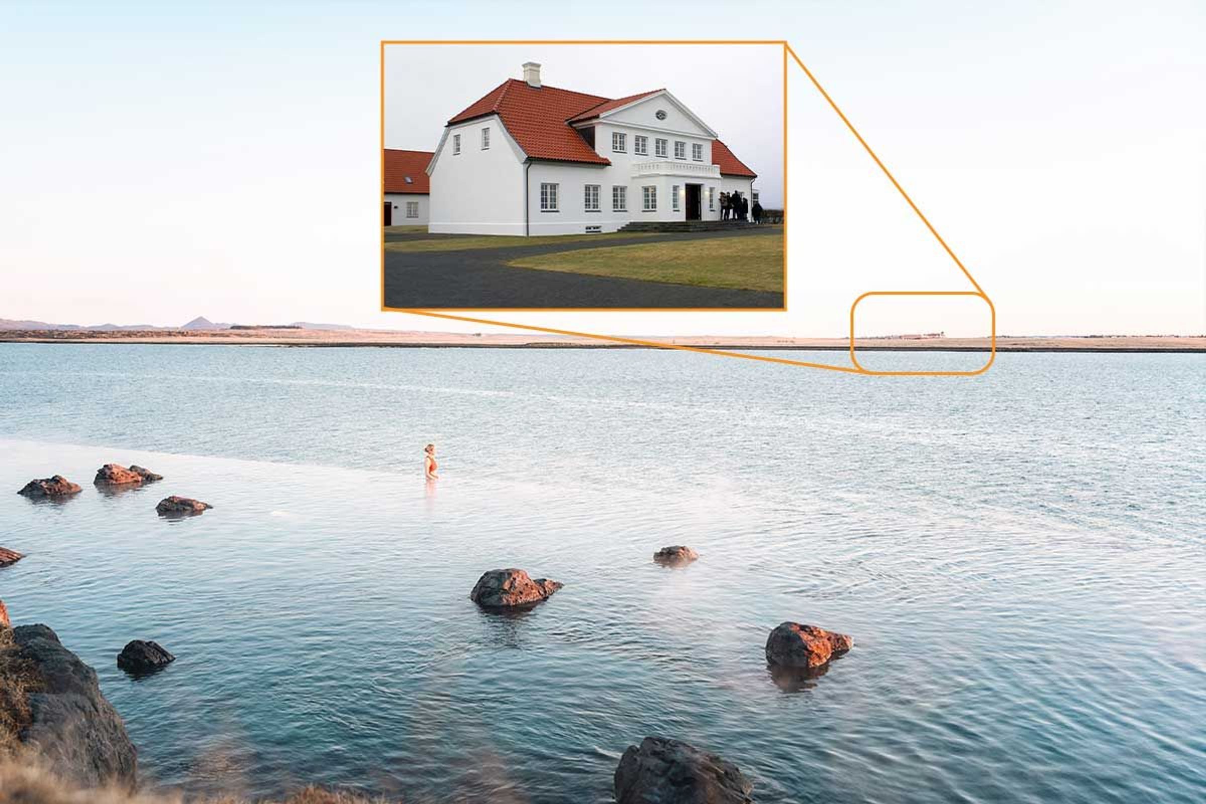 a person is swimming in a lake with a house in the background .