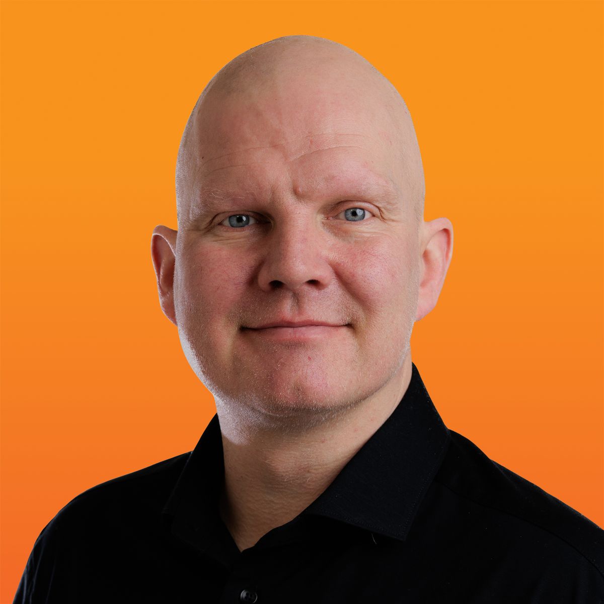 a bald man wearing a black shirt is smiling in front of an orange background .