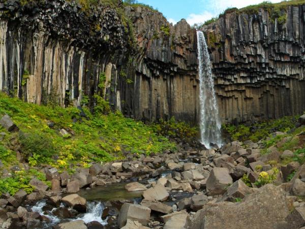 there is a waterfall in the middle of a rocky cliff .