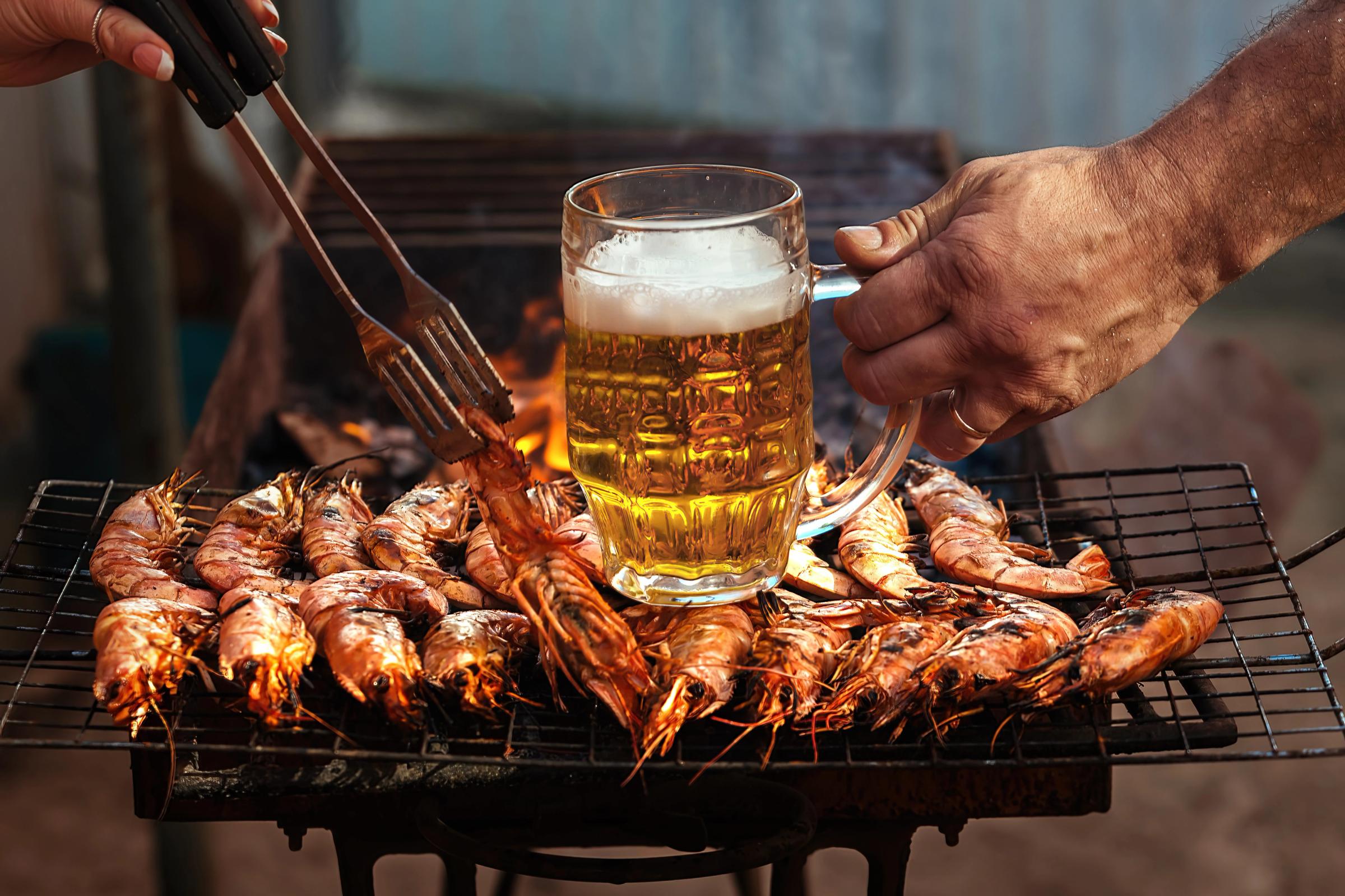 una jarra de cerveza frente a una parrilla de langostinos