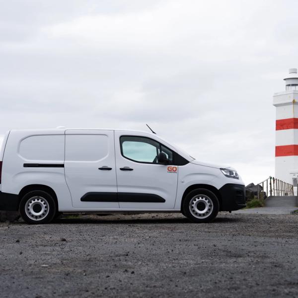 a white van is parked in front of a lighthouse .