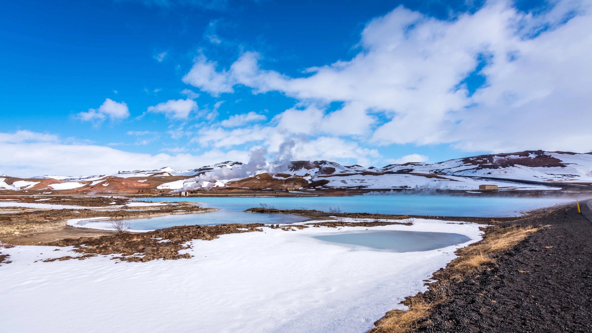 un paysage enneigé avec un lac et des montagnes en arrière-plan .