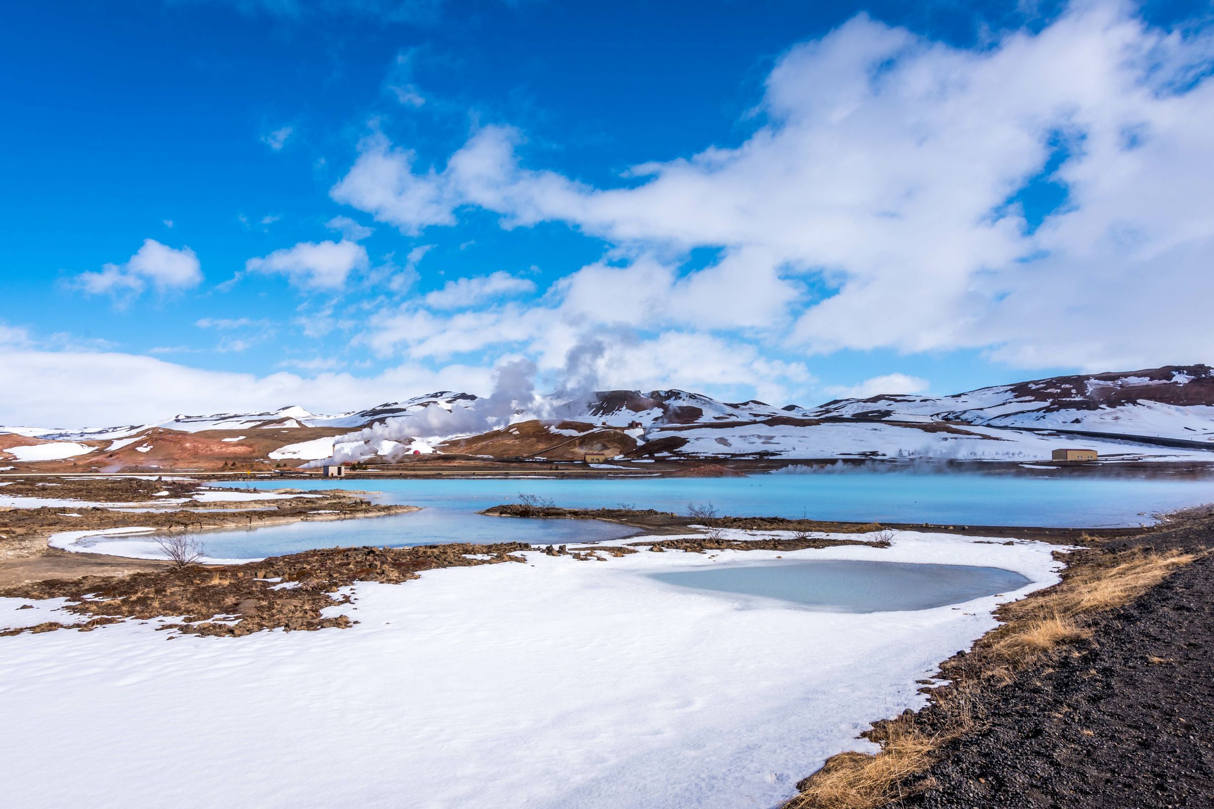 un paysage enneigé avec un lac et des montagnes en arrière-plan .