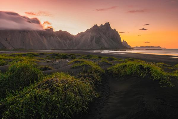 a beach and a mountain with the midnight sun light