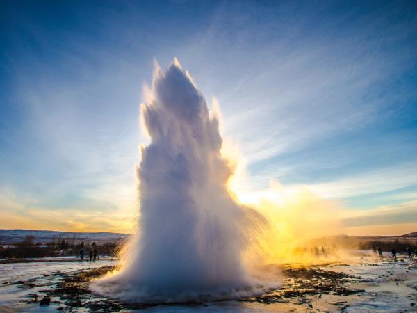 a large geyser is erupting into the air at sunset .