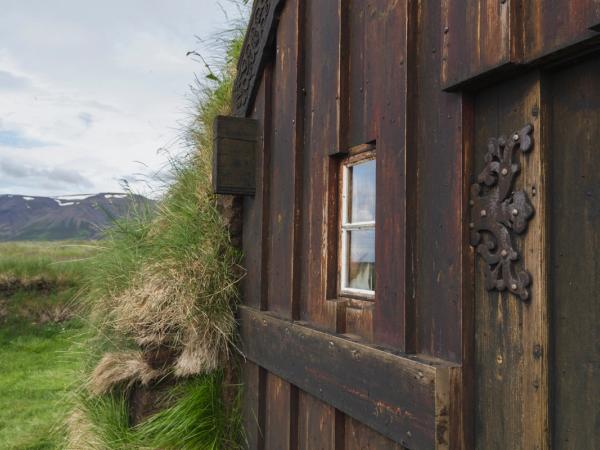 a wooden building with a window in the middle of a grassy field .