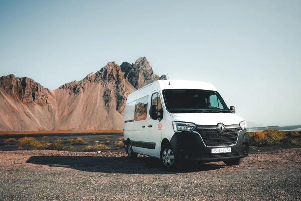a white van is parked in front of a mountain .
