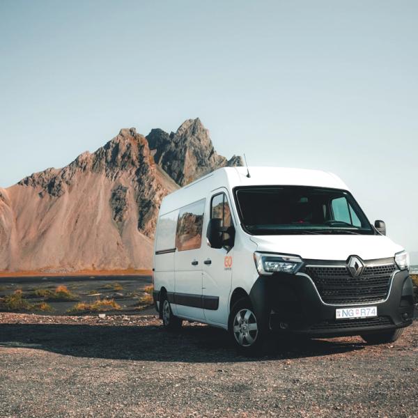 White campervan parked near a beach with mountains in the background