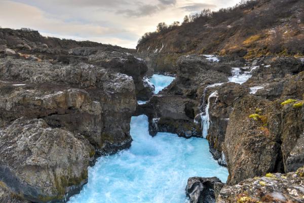 Une cascade se trouve au milieu d'un canyon entouré de rochers à Barnafoss en Islande.