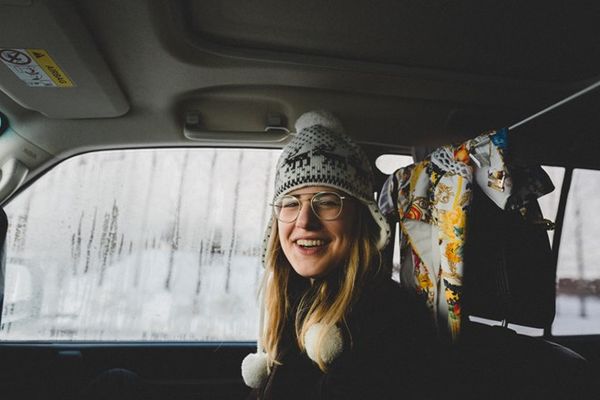 a woman wearing a hat and glasses is sitting in the back seat of a car .