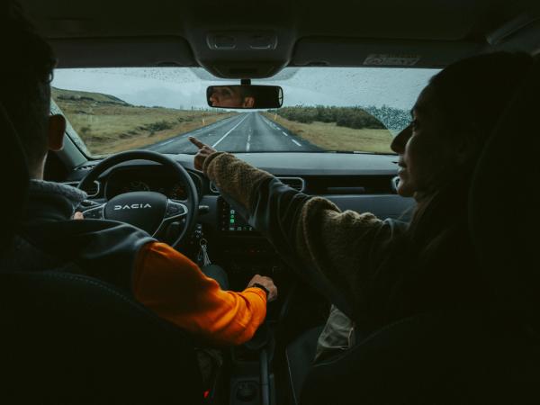 Hombre y mujer dentro de un coche en una carretera islandesa