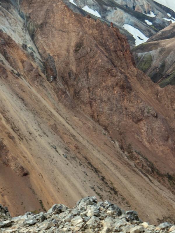 a man with a backpack is standing on top of a mountain looking through binoculars. Hiking in iceland.