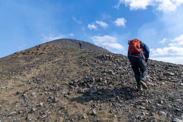 a person with a backpack is walking up a rocky hill .