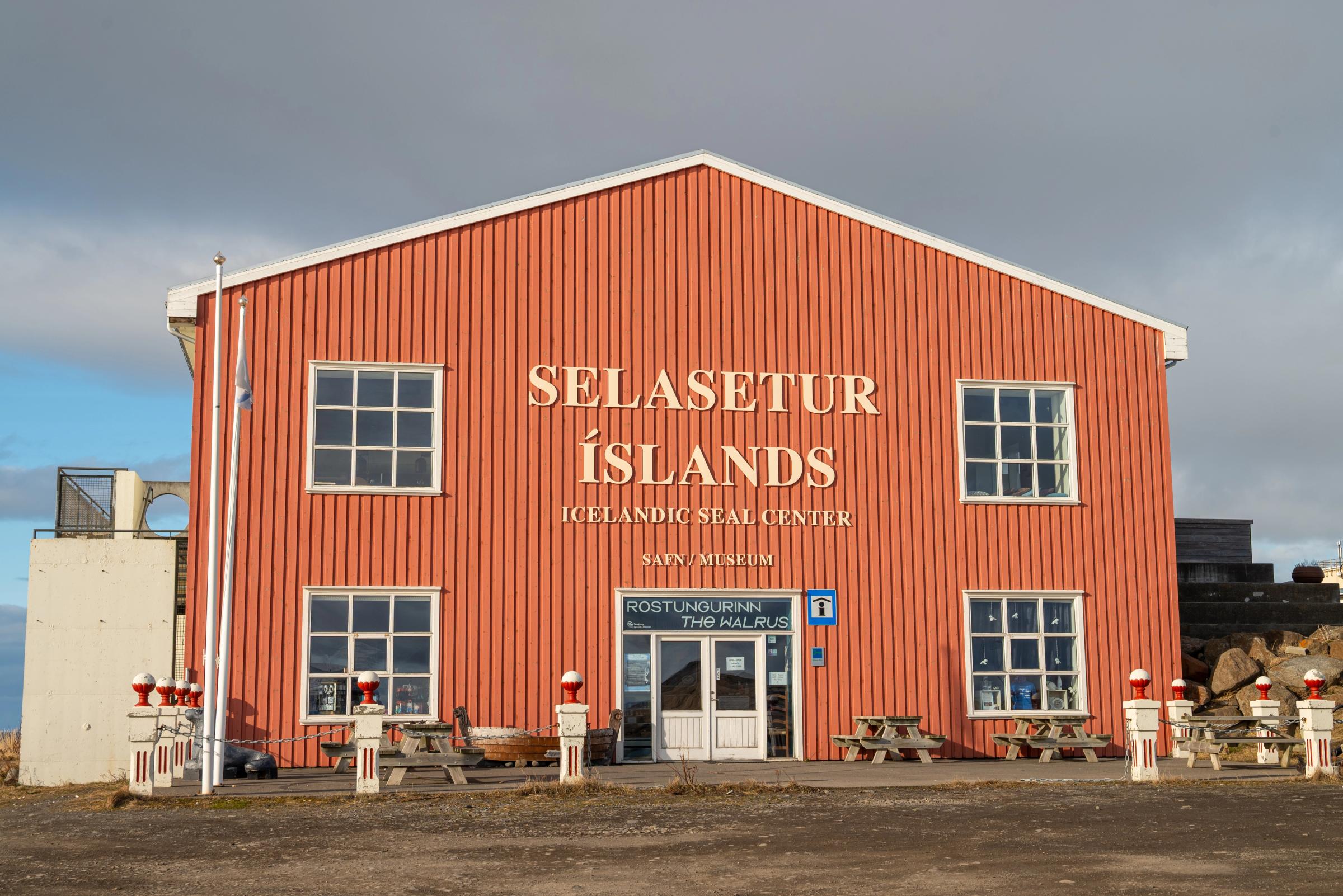 Orange-red building of the Icelandic Seal Center with a cloudy sky.