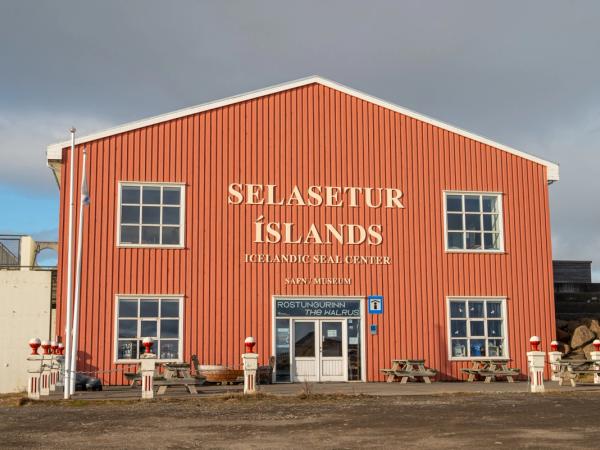 Orange-red building of the Icelandic Seal Center with a cloudy sky.