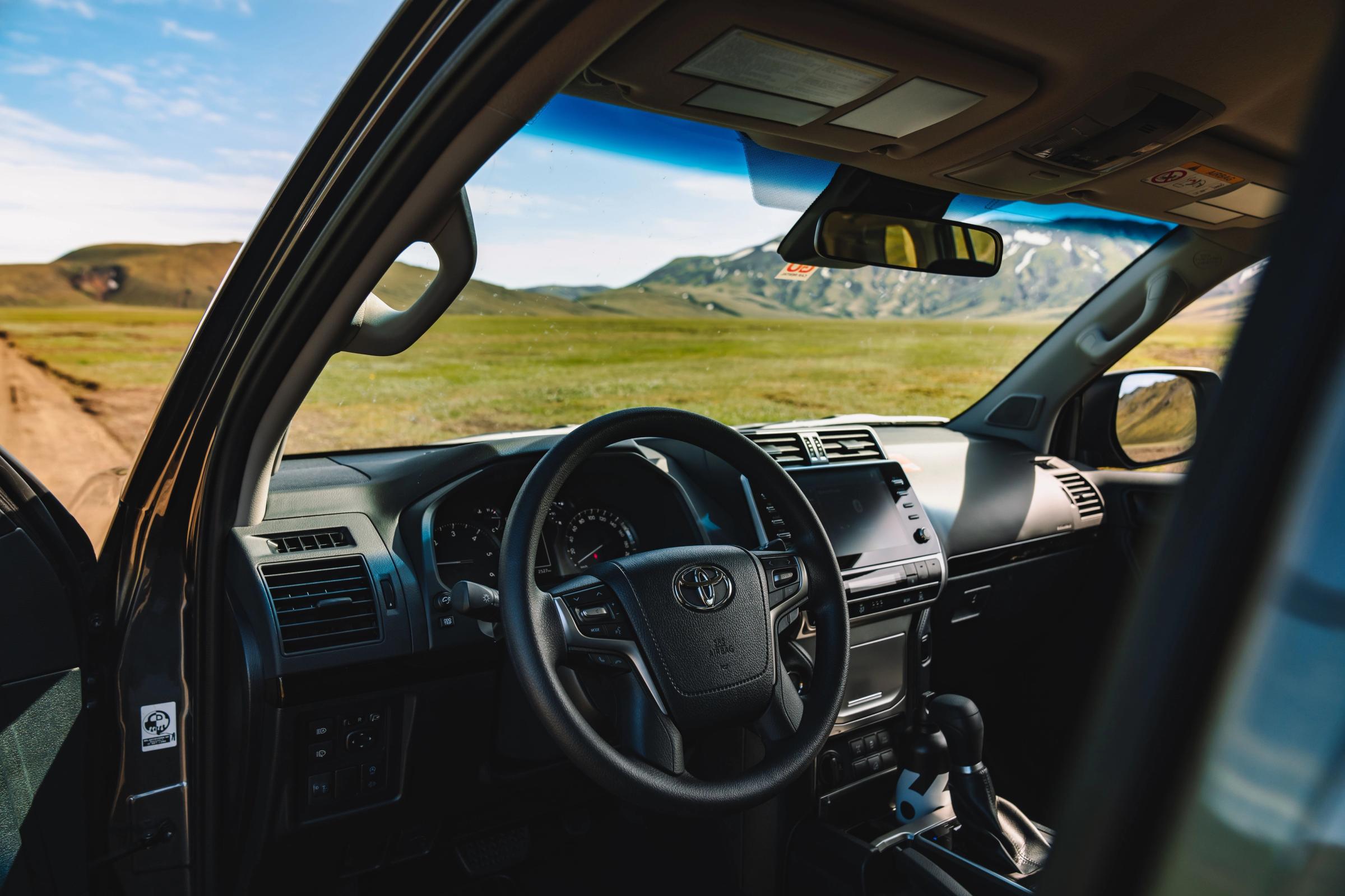 Toyota Land Cruiser interior with steering wheel, dashboard and touchscreen, open landscape ahead