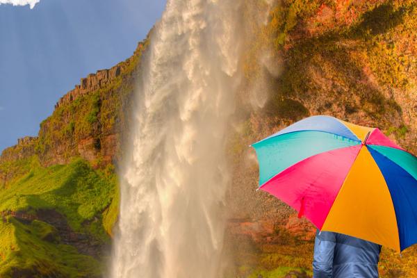 Girl with umbrella in front of Iceland Waterfall