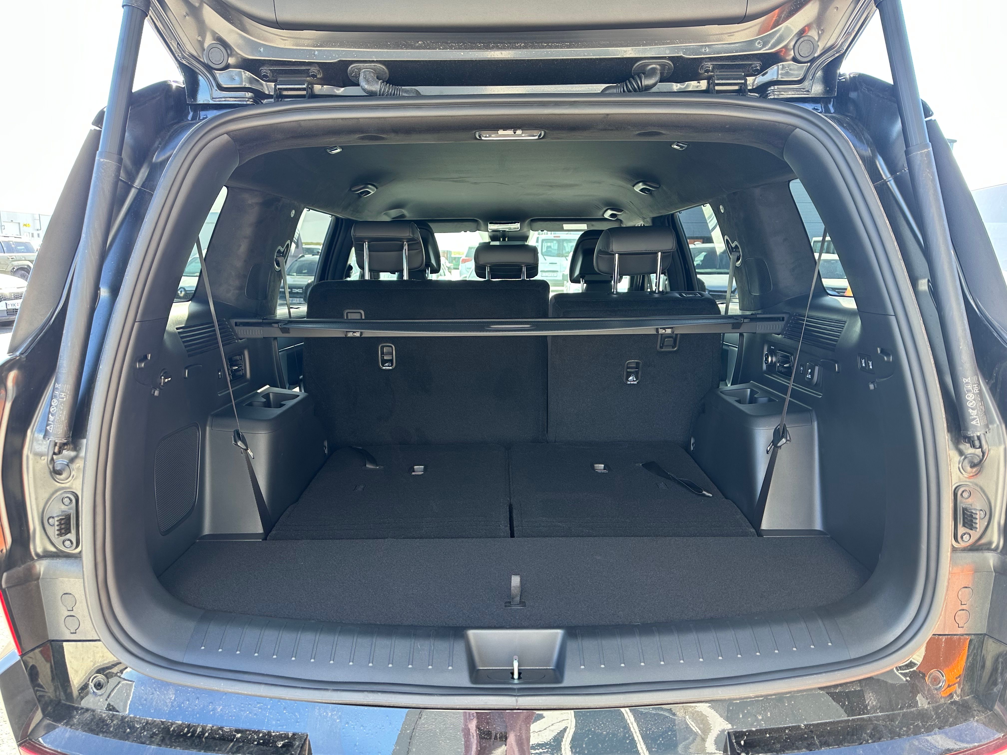 Open trunk of an SUV showing third-row seats folded down and a cargo cover.