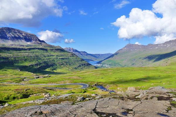 a road leading down ti a village at the base of a fiord