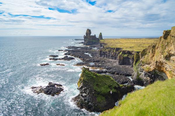 a view of a cliff overlooking the ocean with rocks and grass .