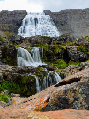 a waterfall is surrounded by rocks in the middle of a mountain dynjandi in iceland.
