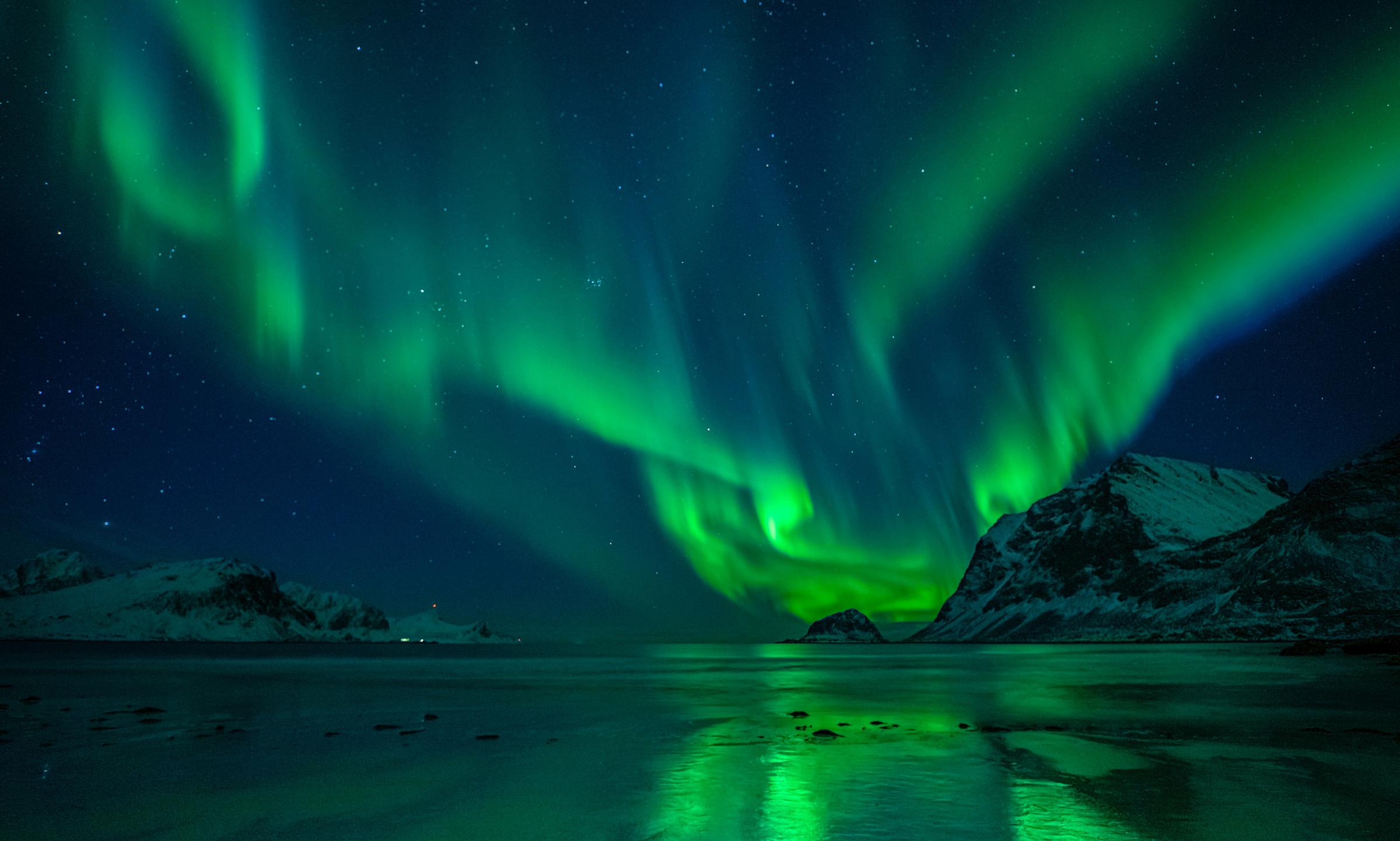 the aurora borealis is reflected in the water of a lake .