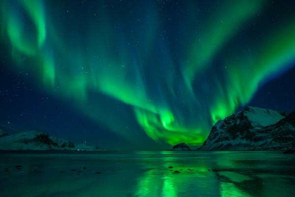 the aurora borealis is reflected in the water of a lake .