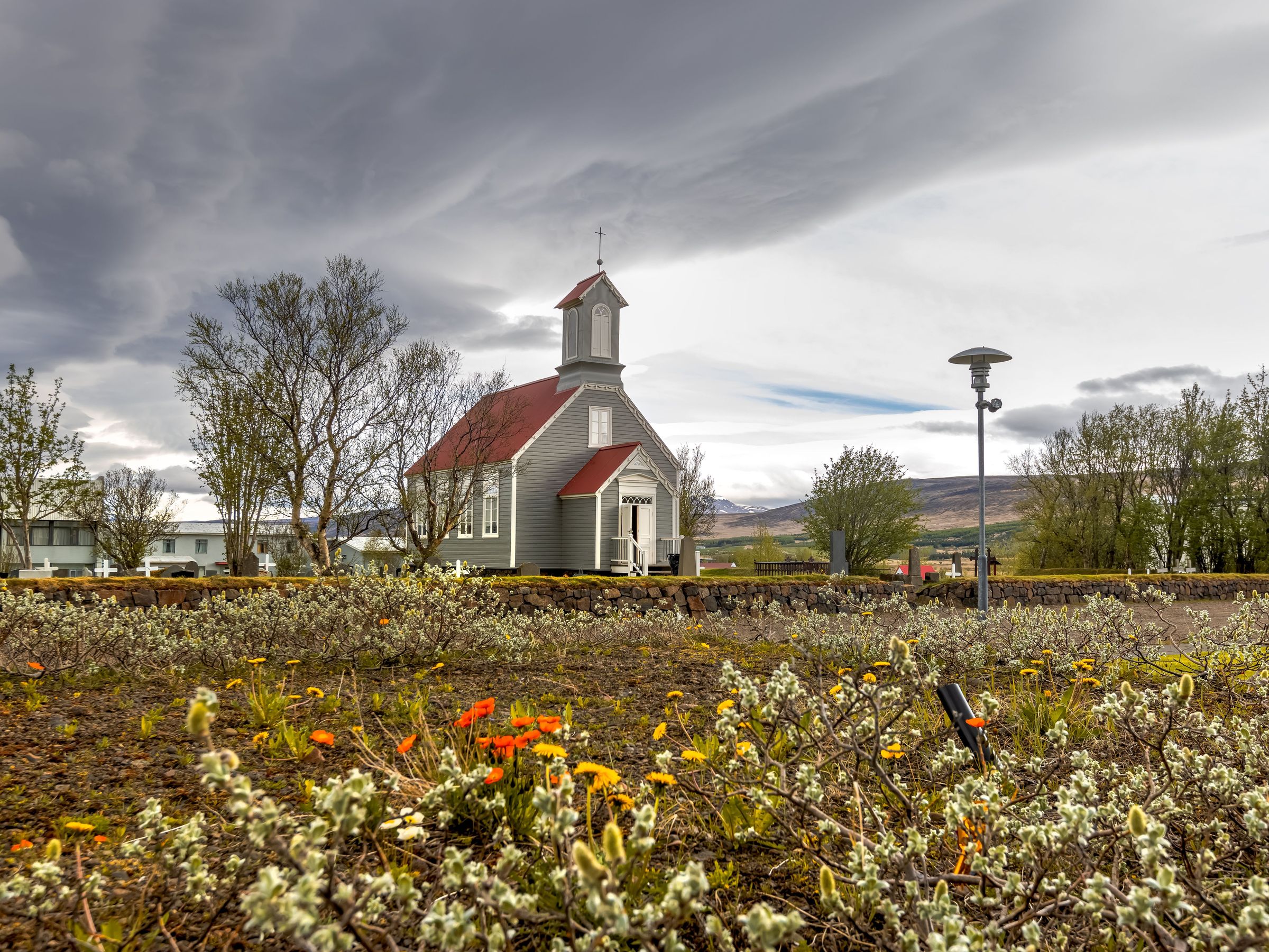 una pequeña iglesia con techo rojo está rodeada por un campo de flores .