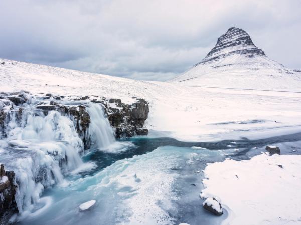 un paisaje nevado con un río y una montaña