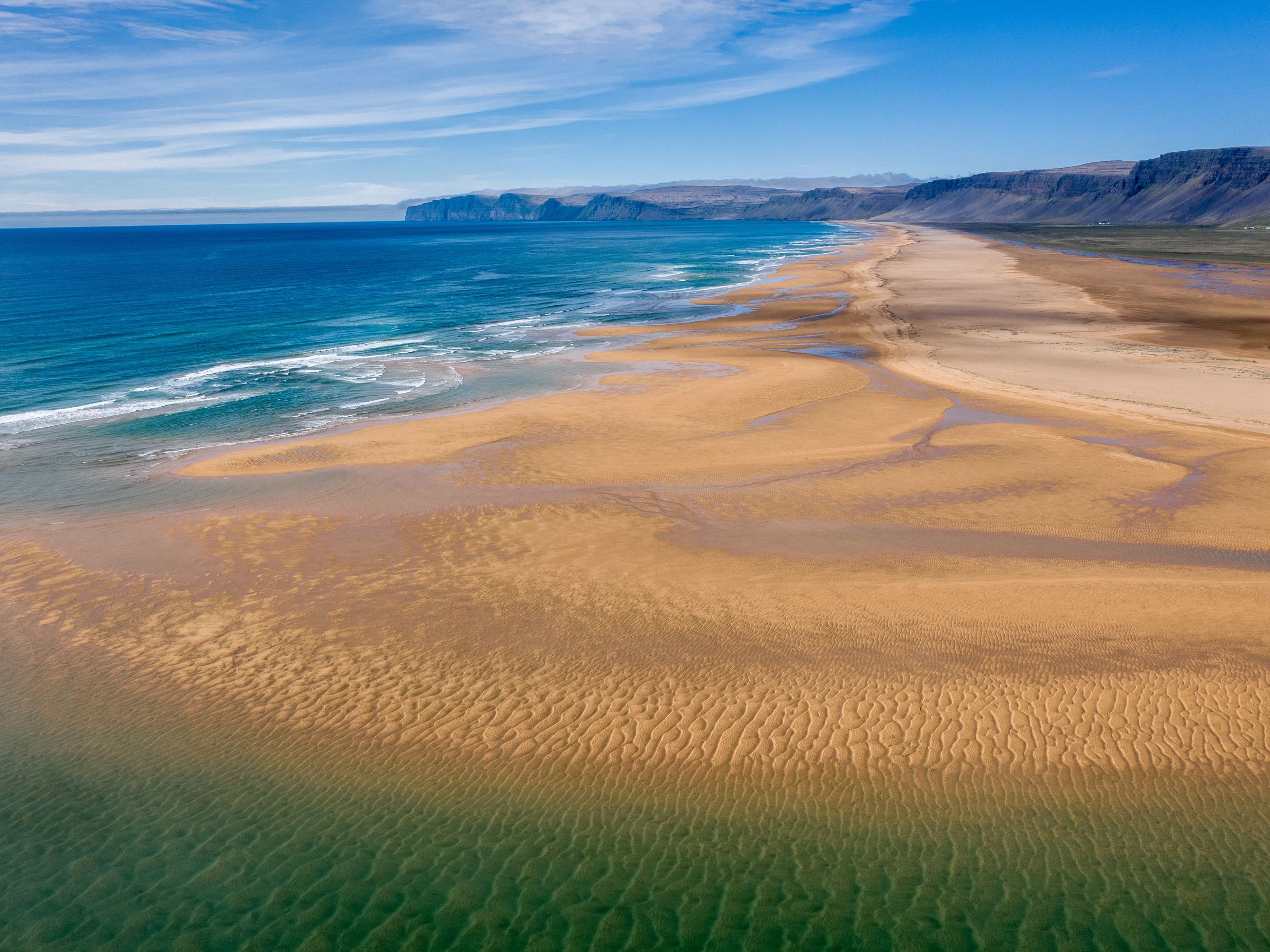 una vista aérea de una larga playa de arena junto al océano.