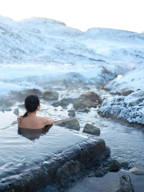 a woman is taking a bath in a hot spring in the snow .