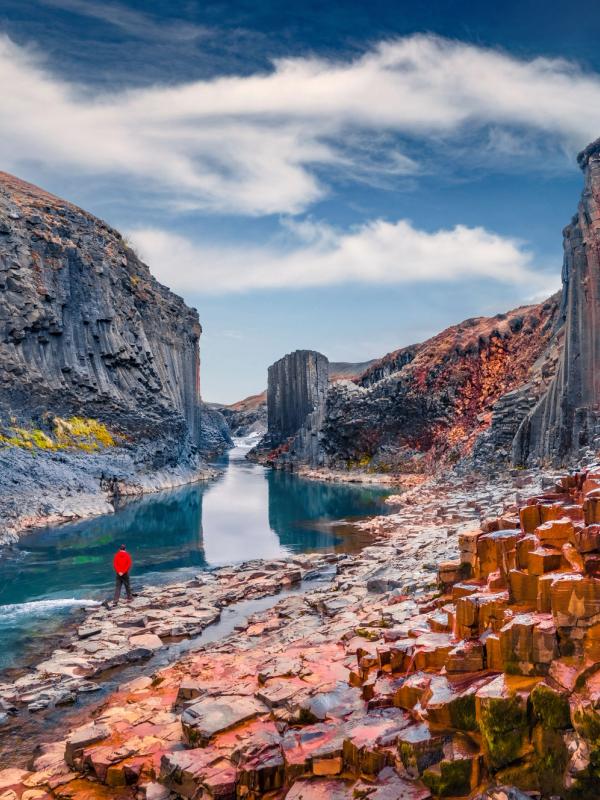 Turista caminando en el fondo del Cañón de Studlagil con columnas de basalto.