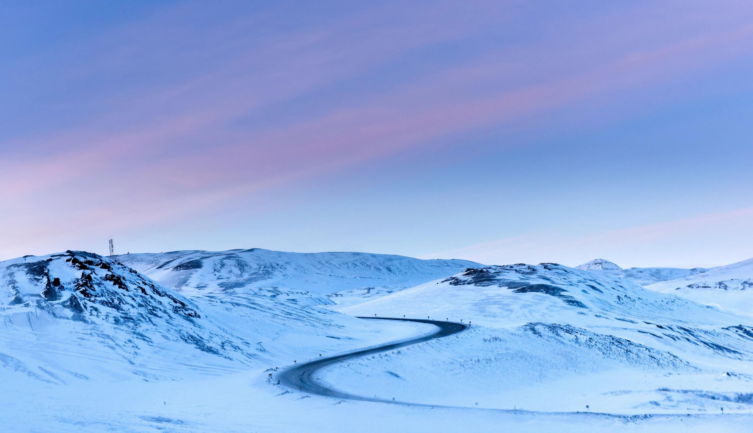 a snowy mountain with a road going through it .