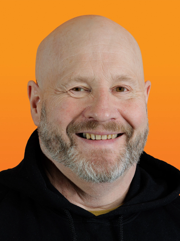 a smiling bald man with a beard wearing a black hoodie