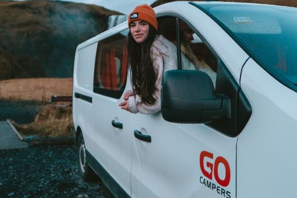 a woman is leaning out of the window of a white van .