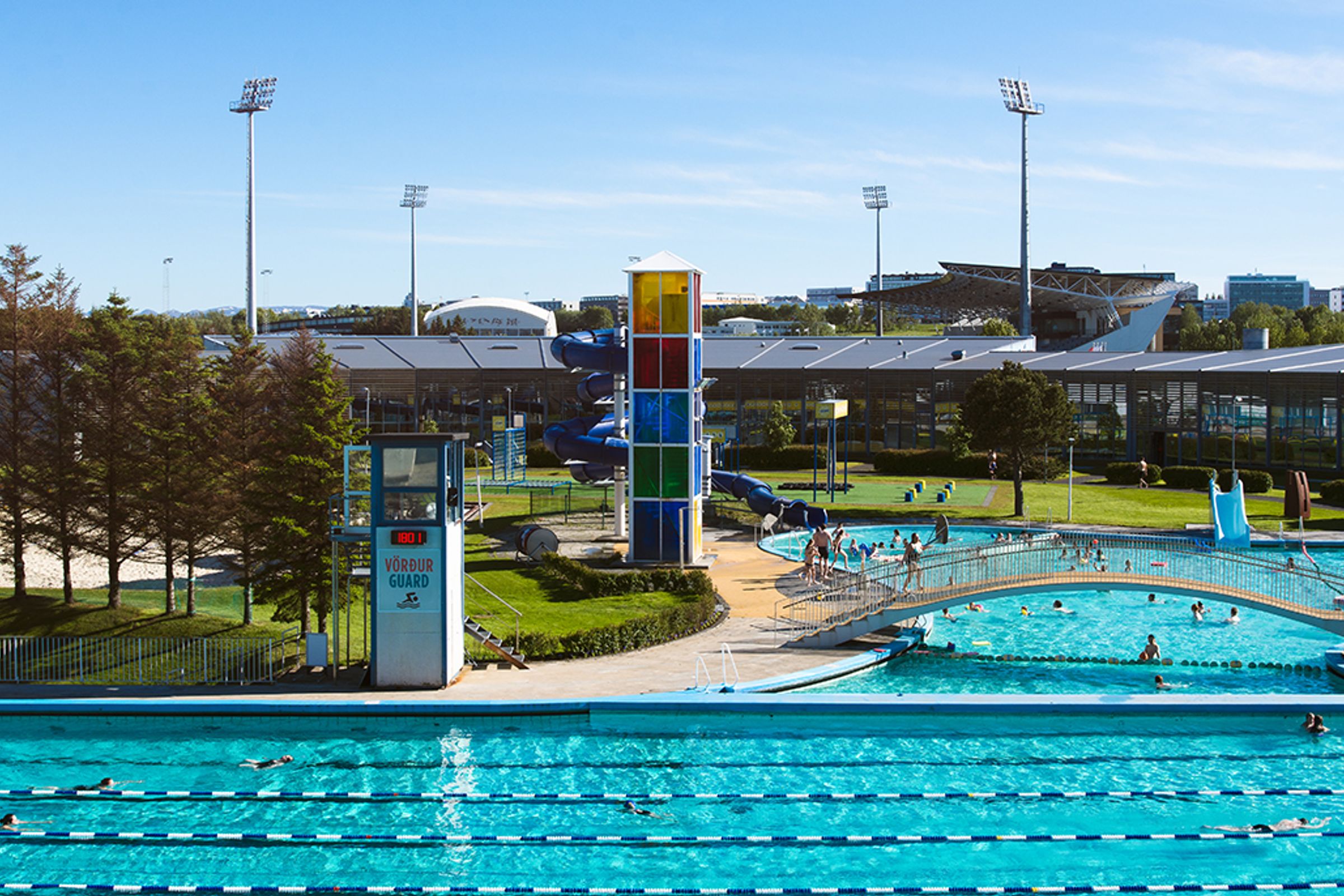 a swimming pool with a water slide in the background and people swimming in it .