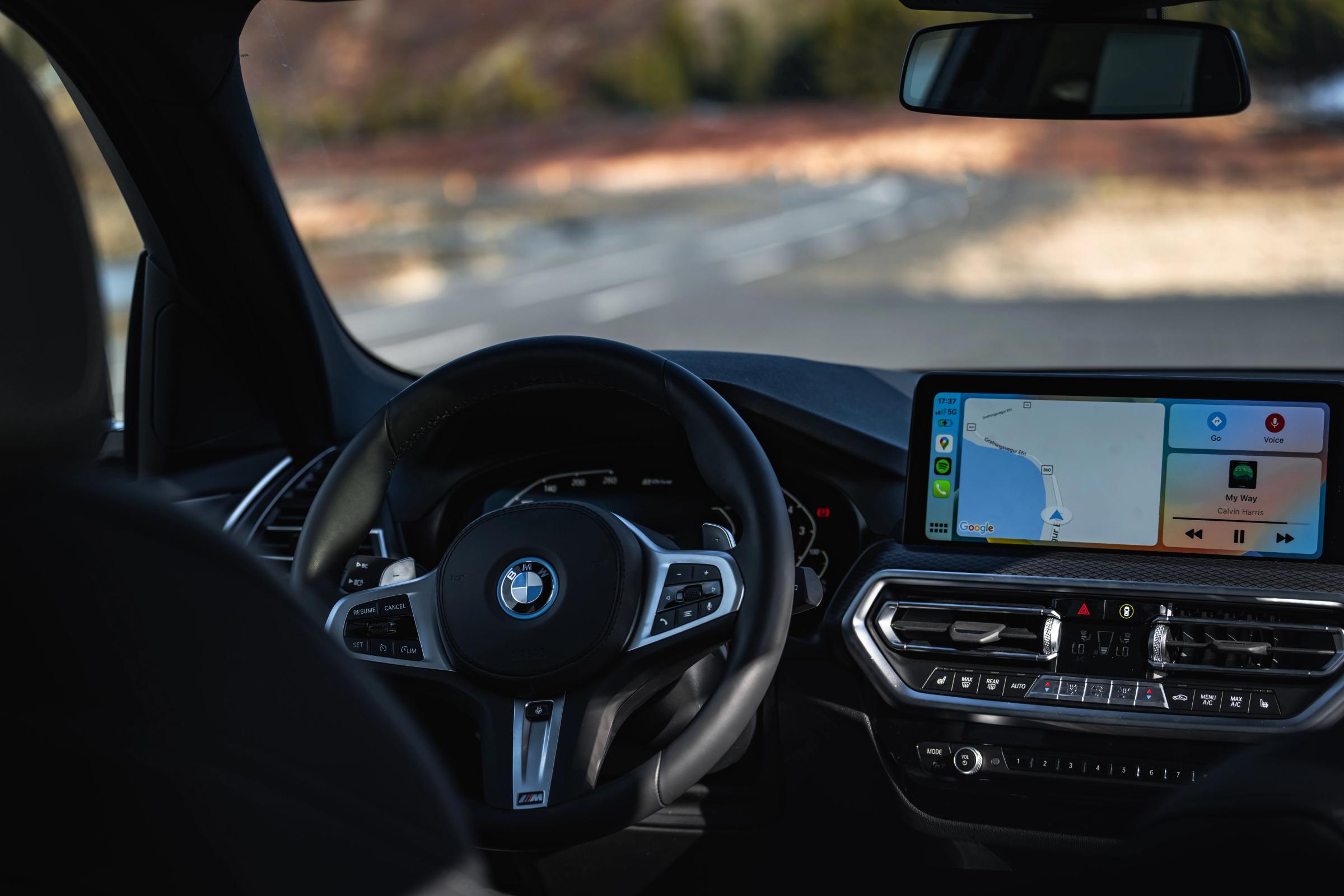 Tableau de bord intérieur du X3 Vue de l’intérieur d’une BMW X3 avec volant et écran tactile affichant le système de navigation