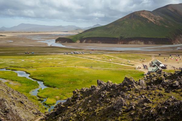 une vue d'une vallée avec des montagnes en arrière-plan et une rivière qui la traverse.