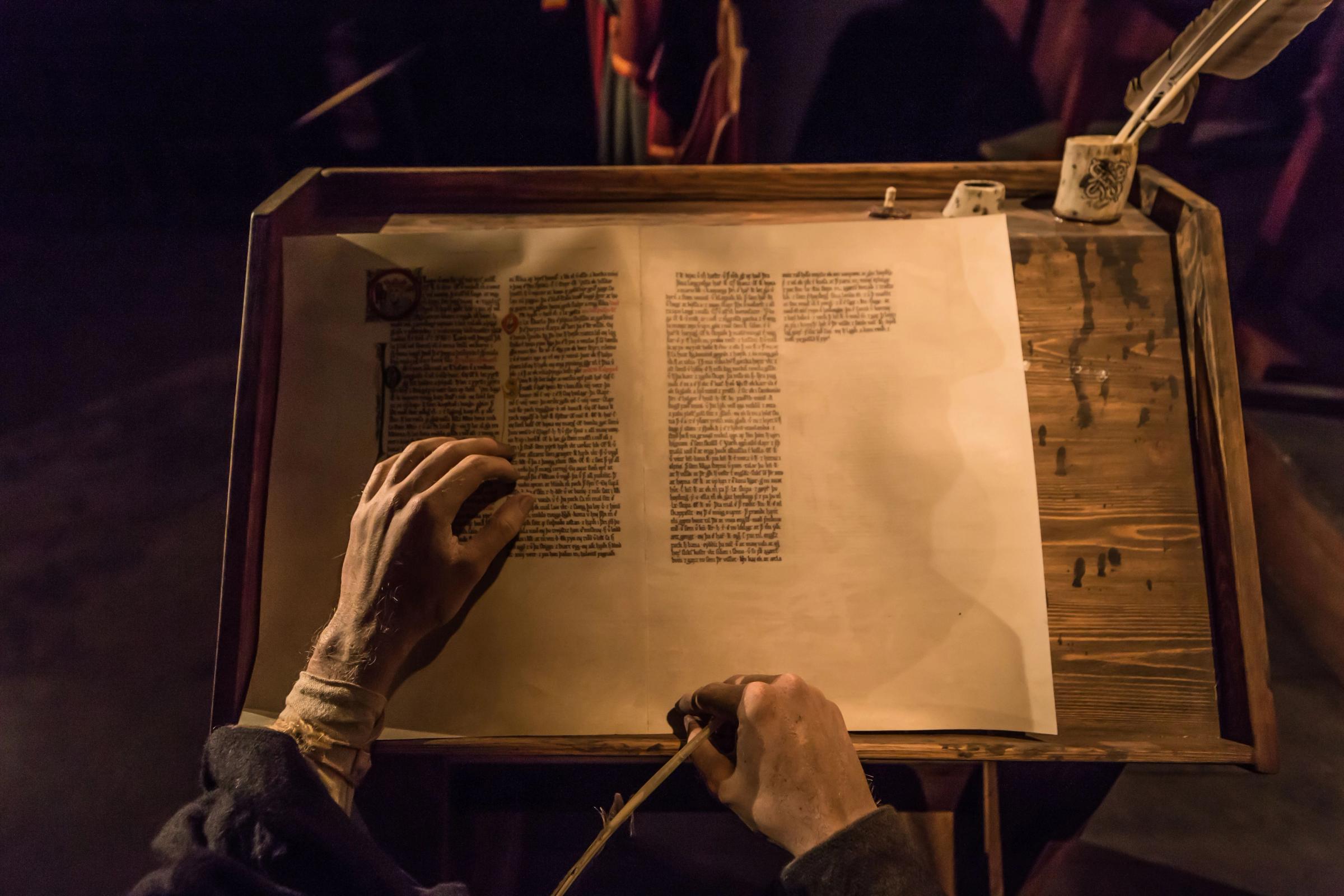 a person is writing on a piece of paper with a feather pen .