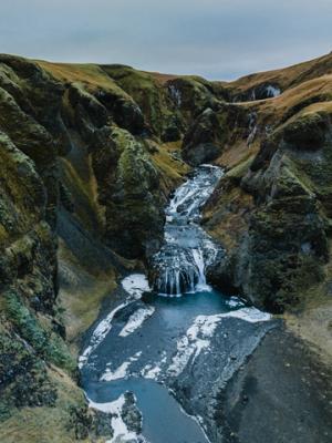 A river with waterfalls flows through a deep, moss-covered canyon.