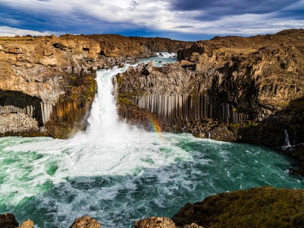 Aldeyjarfoss waterfall with a rainbow in the water.