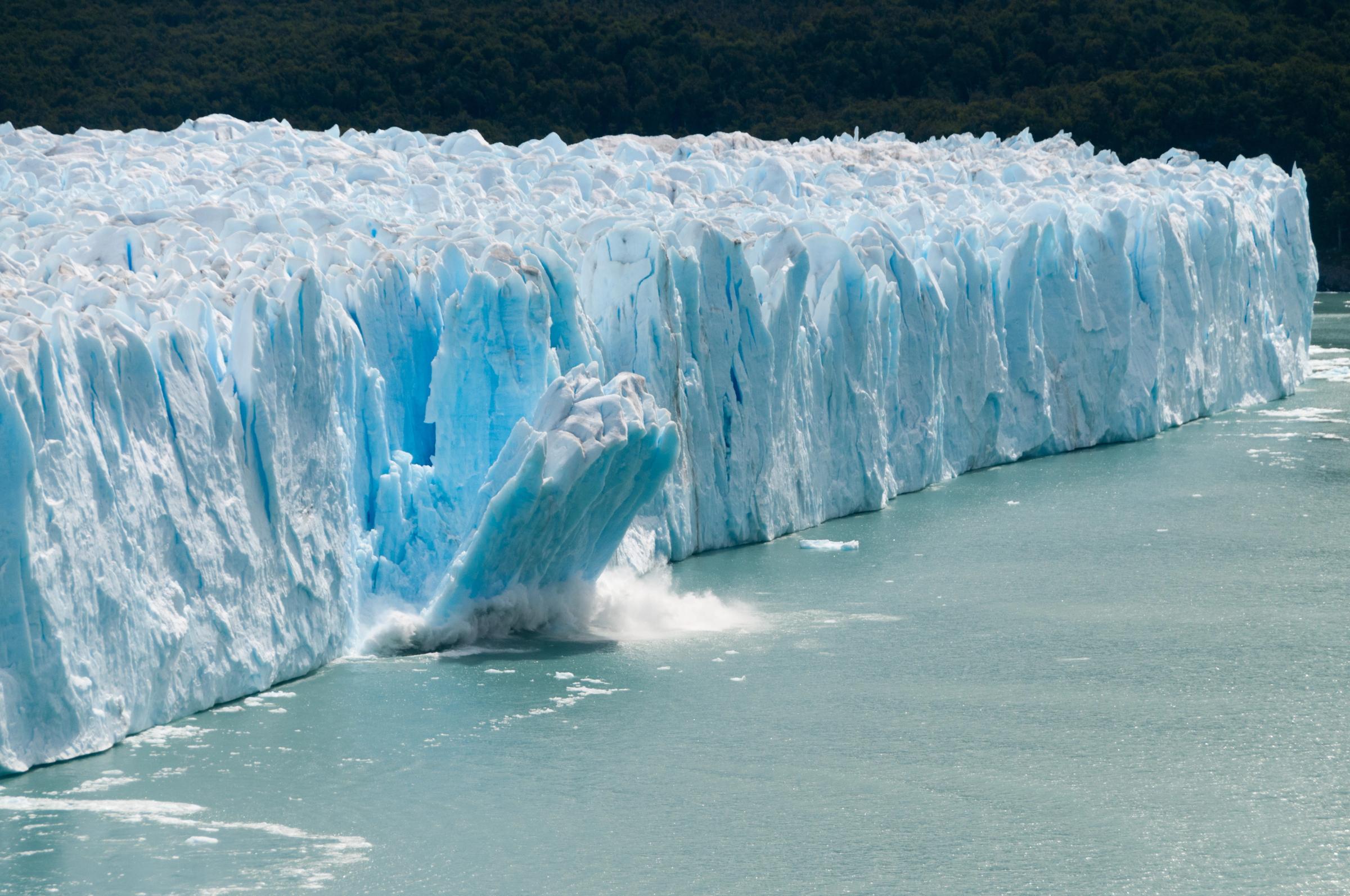 a piece of ice breaking apart from a glacier and falling into the water