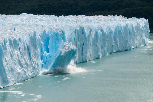 a piece of ice breaking apart from a glacier and falling into the water