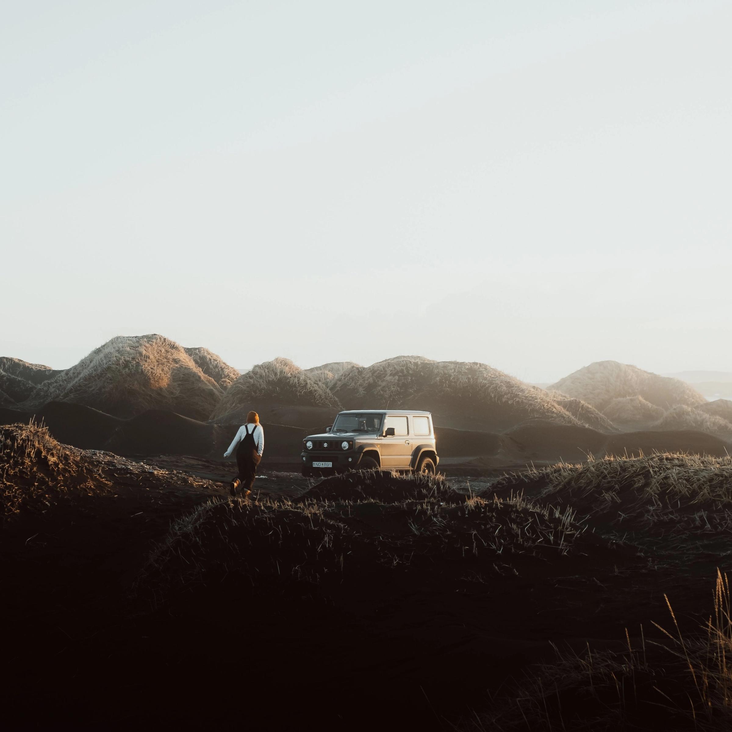 una mujer junto a un coche 4x4 rodeada de colinas