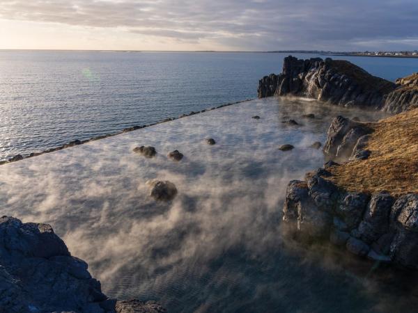 there is a swimming pool in the middle of the ocean surrounded by rocks .