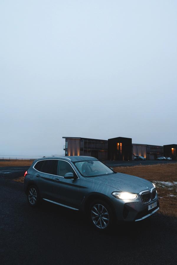 SUV BMW X3 de location en Islande, garé sur un parking près de bâtiments d’hébergement au crépuscule