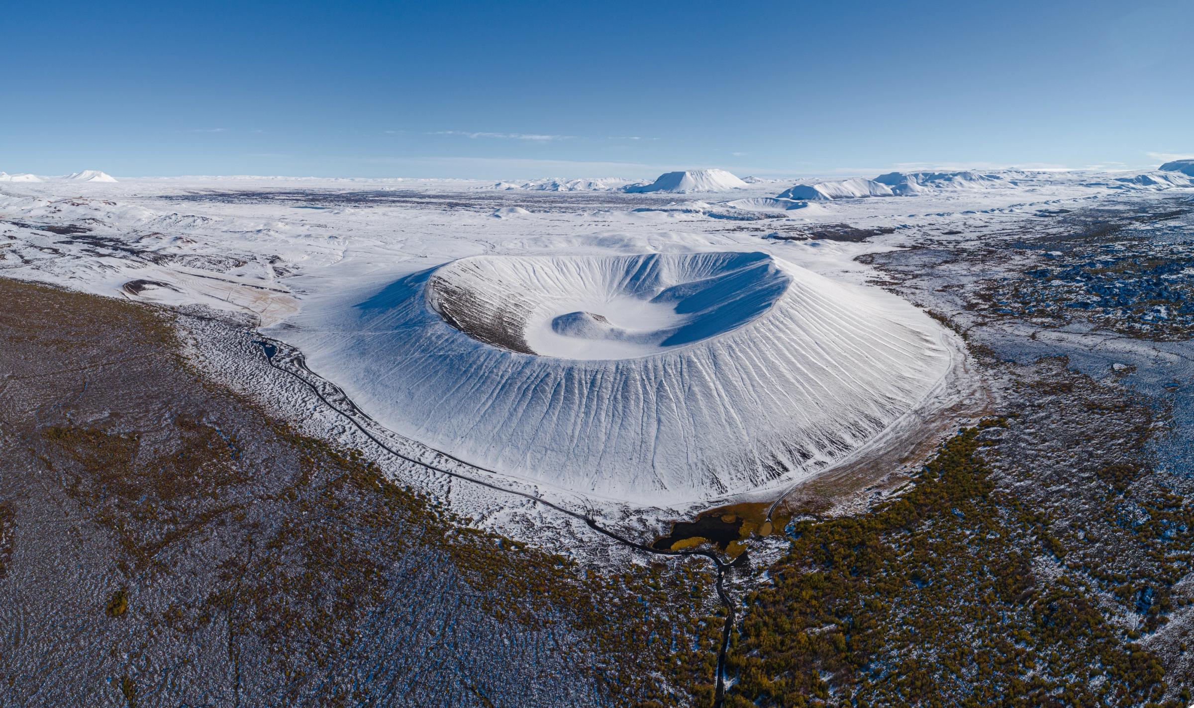 una vista aérea de un gran cráter en medio de un paisaje nevado.