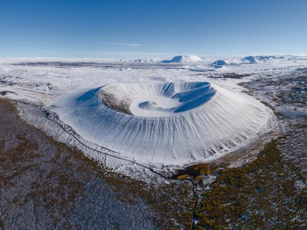 an aerial view of a large crater in the middle of a snowy landscape .