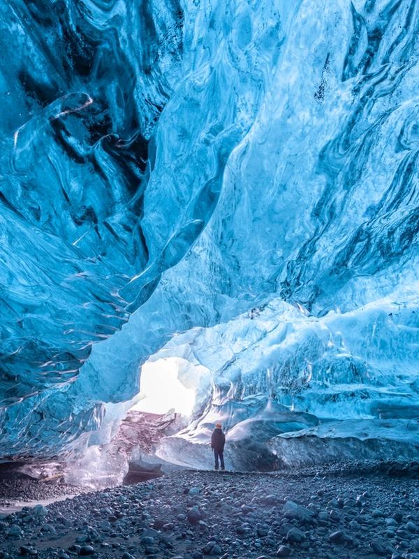 a man is standing inside of an ice cave on a trip in iceland.